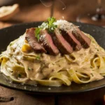 Creamy steak pasta served on a rustic plate with seared steak slices and parsley garnish